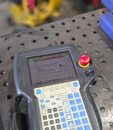 FANUC teach pendant resting on the welding table